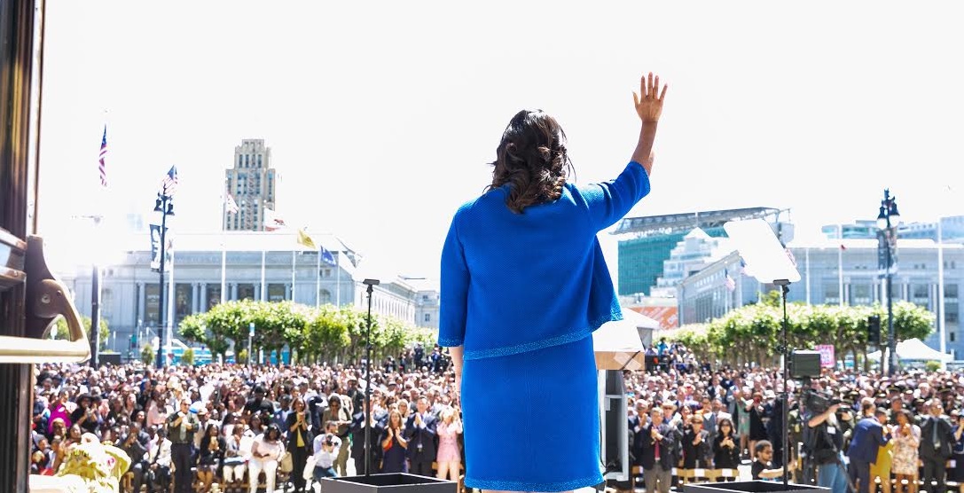 Photo from behind Mayor London Breed as she waves to the crowd at her inauguration