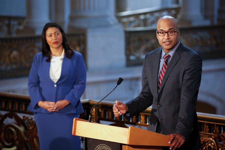Manohar Raju, selected by Mayor London Breed (left) as the city’s new public defender, speaks to the media at City Hall.